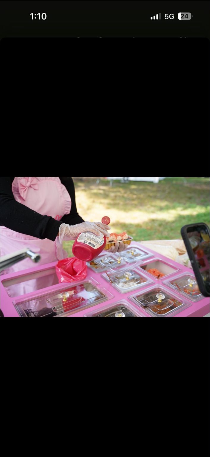 A LovelyEatz attendant adding strawberry drizzle to a dessert at the pink treat cart